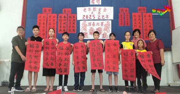 陈义军（左）在杨金花（右起）、张丽丽陪同下，与小学高年组得奖者合影。