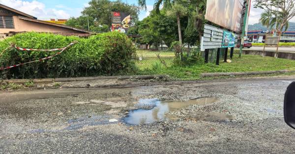 红绿灯叉路口因地下水管爆破渗水，以致沥青路面软化被辗成路洞，危及民众。