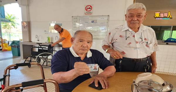 钟德生（坐者）向龙兆宏展示因行动不便，未曾亲自到超市“扫卡”消费的大马卡。