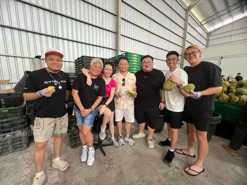 黄泳铭（右2）与车队队友们开心品尝榴梿。